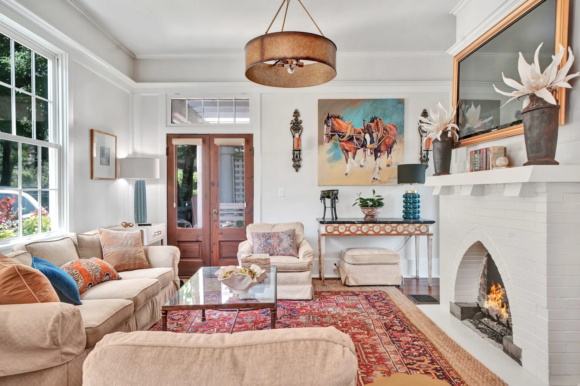 Bright living room with a painted brick fireplace and tall windows